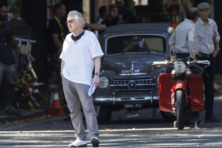 a man walking down a street next to a car