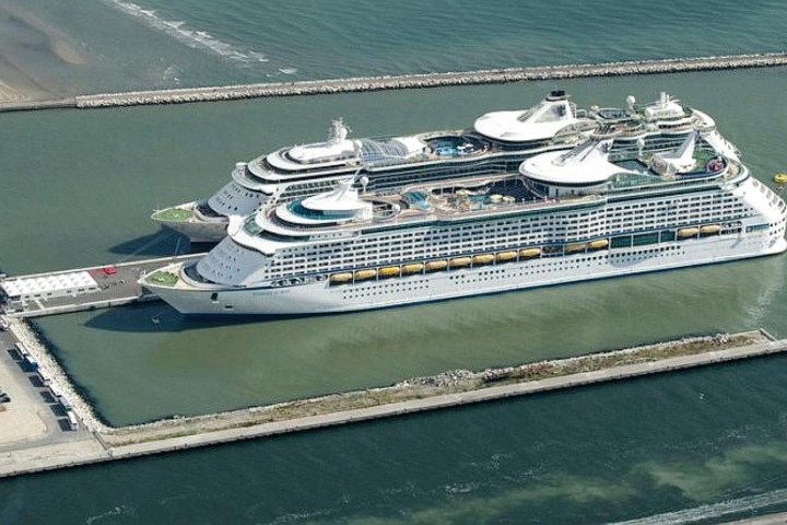 Two large cruise ships docked side by side in a rectangular harbor area.