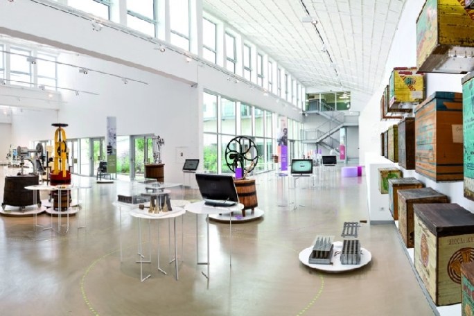 Bright modern museum with industrial artifacts and colorful vintage boxes on display.